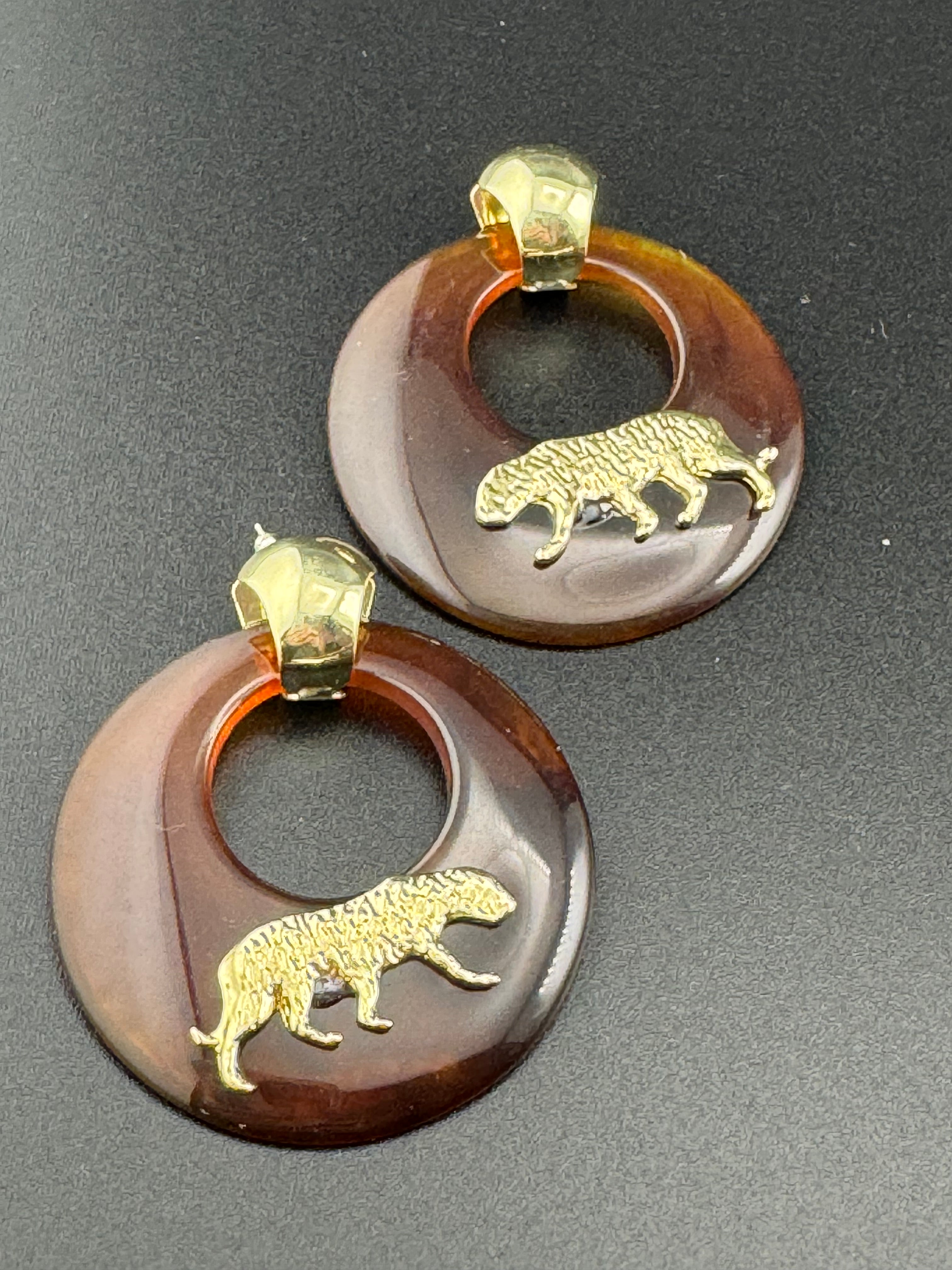 Oversized brown tortoiseshell dangly acrylic hoop earrings with gold big cat leopards , pierced ears.
