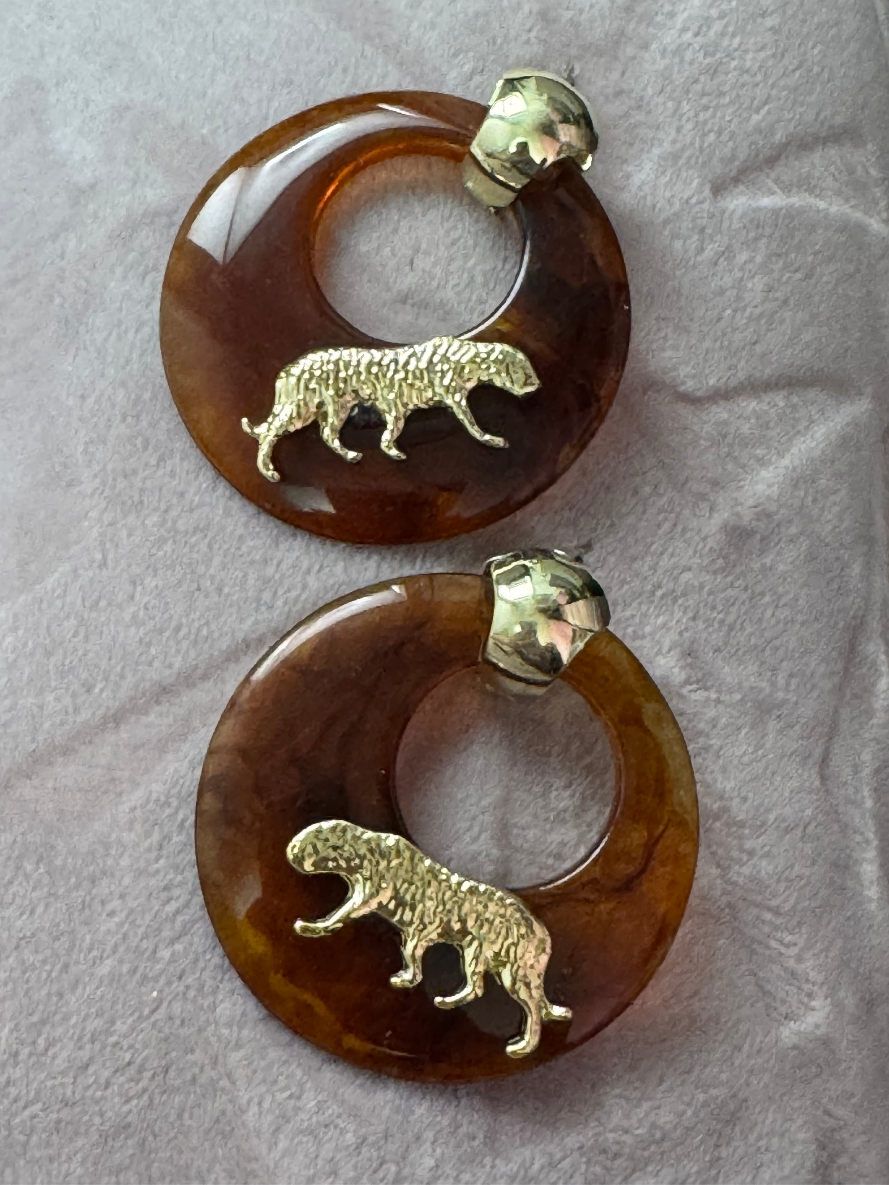 Oversized brown tortoiseshell dangly acrylic hoop earrings with gold big cat leopards , pierced ears.