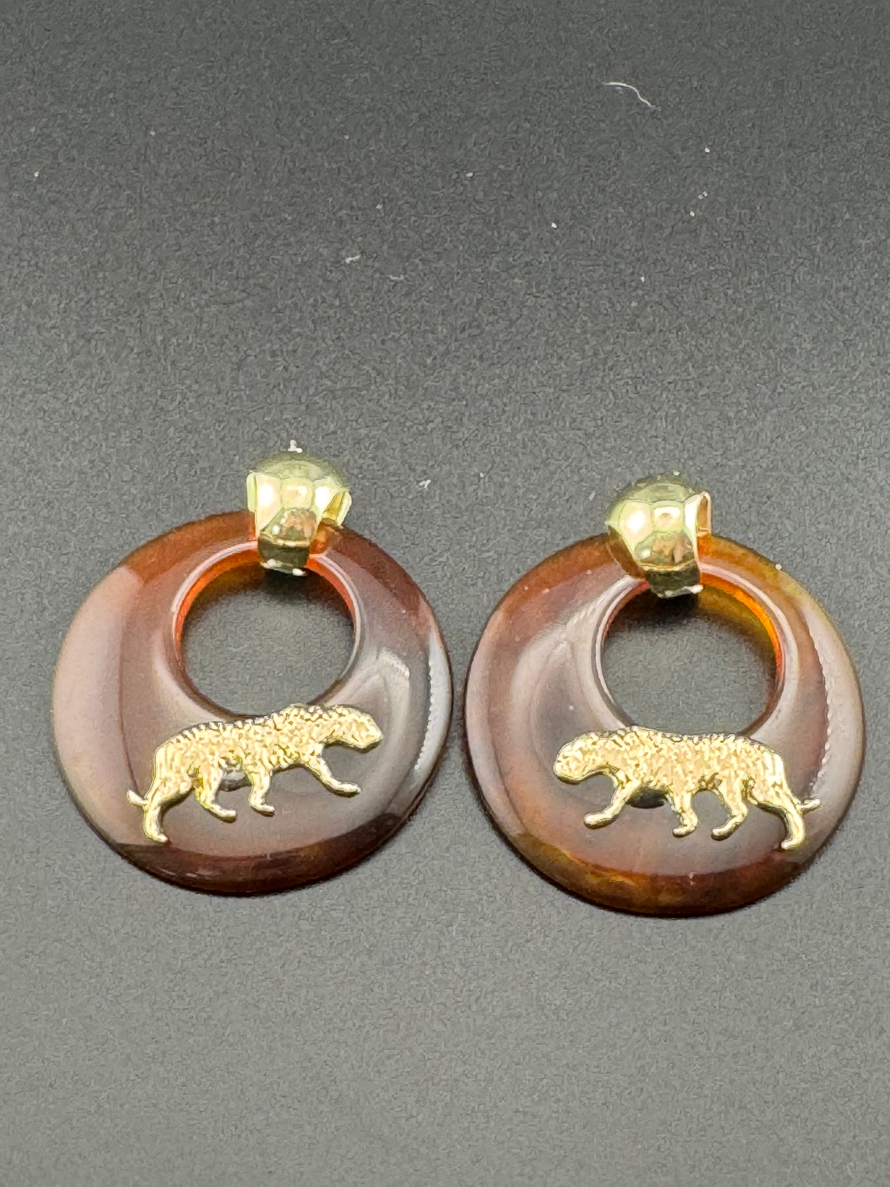 Oversized brown tortoiseshell dangly acrylic hoop earrings with gold big cat leopards , pierced ears.
