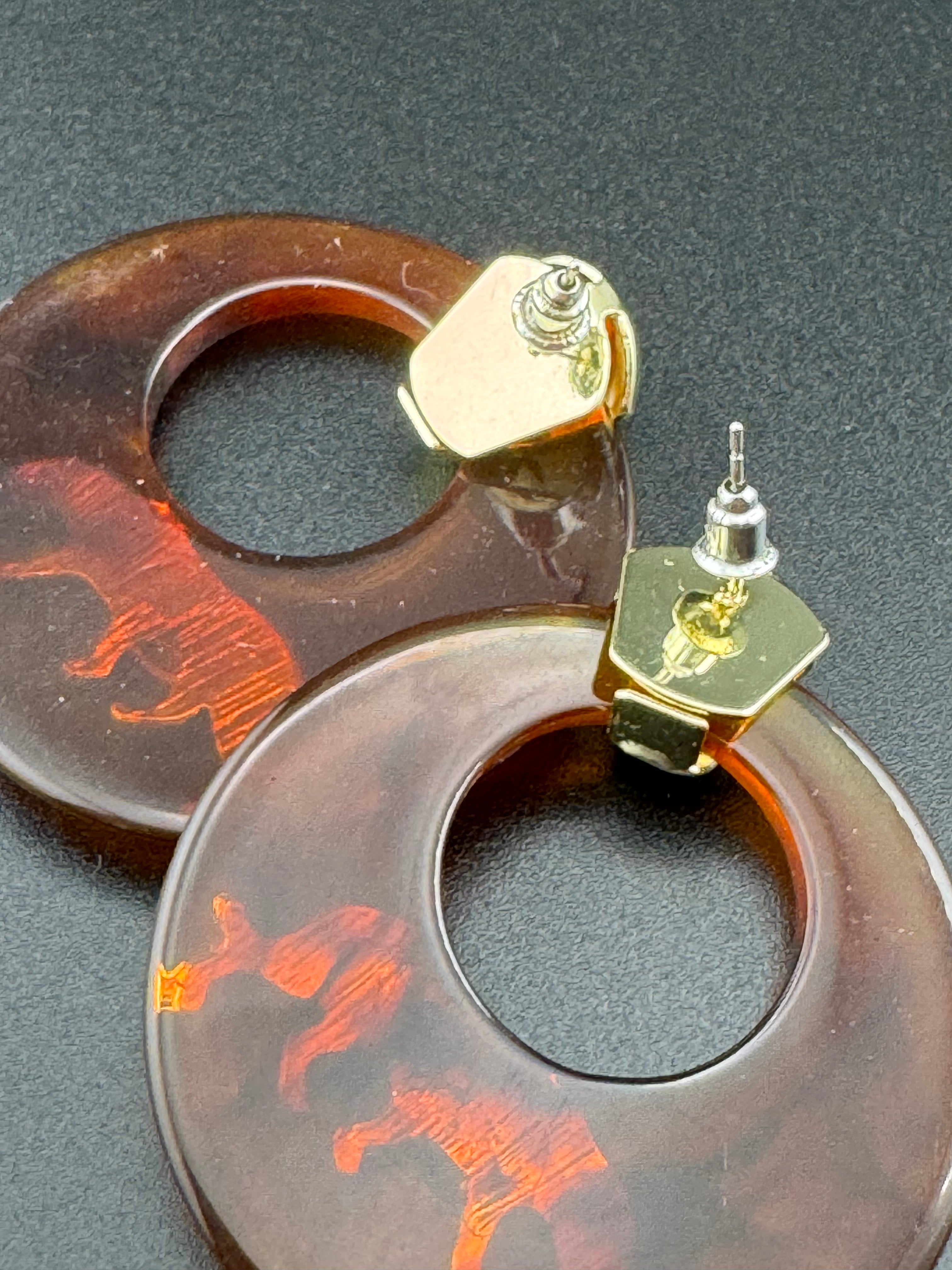 Oversized brown tortoiseshell dangly acrylic hoop earrings with gold big cat leopards , pierced ears.