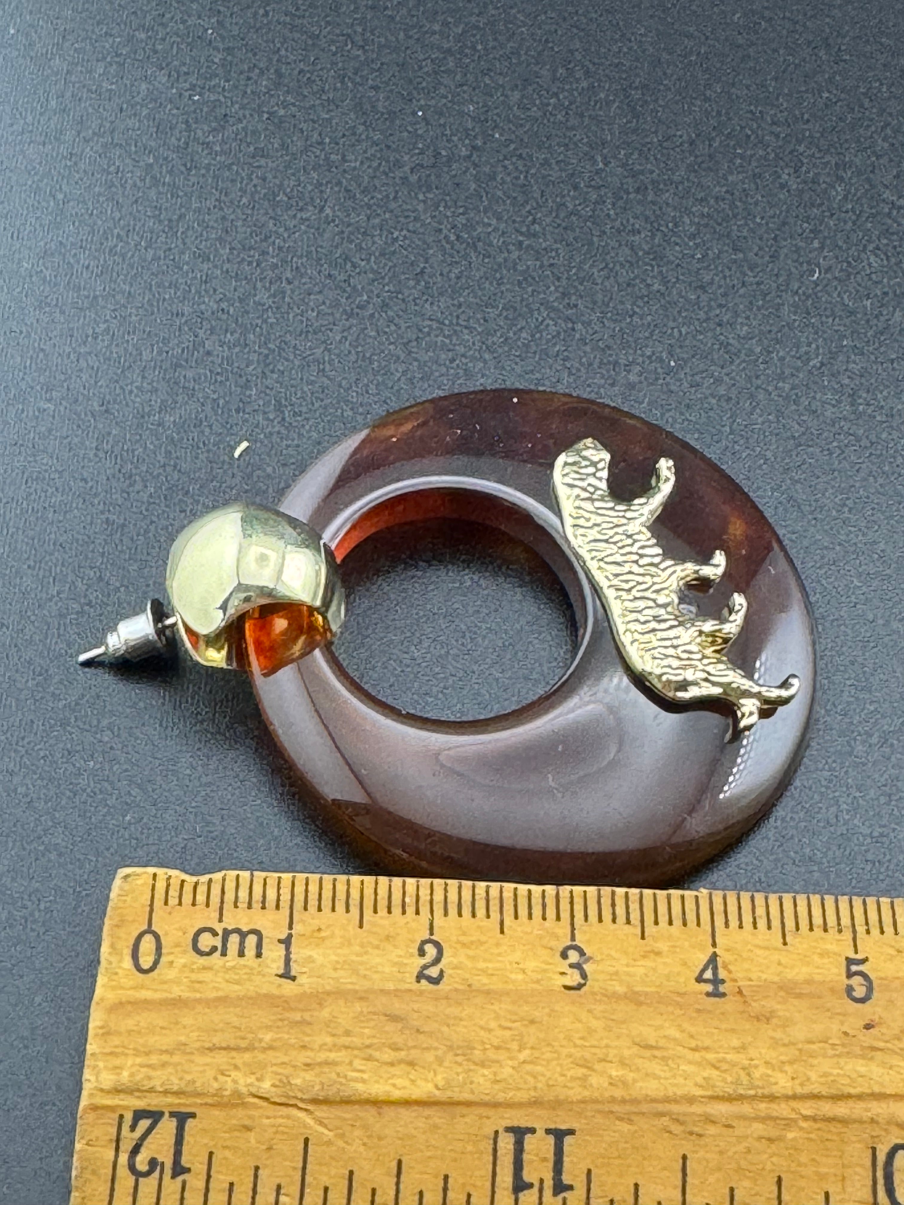 Oversized brown tortoiseshell dangly acrylic hoop earrings with gold big cat leopards , pierced ears.
