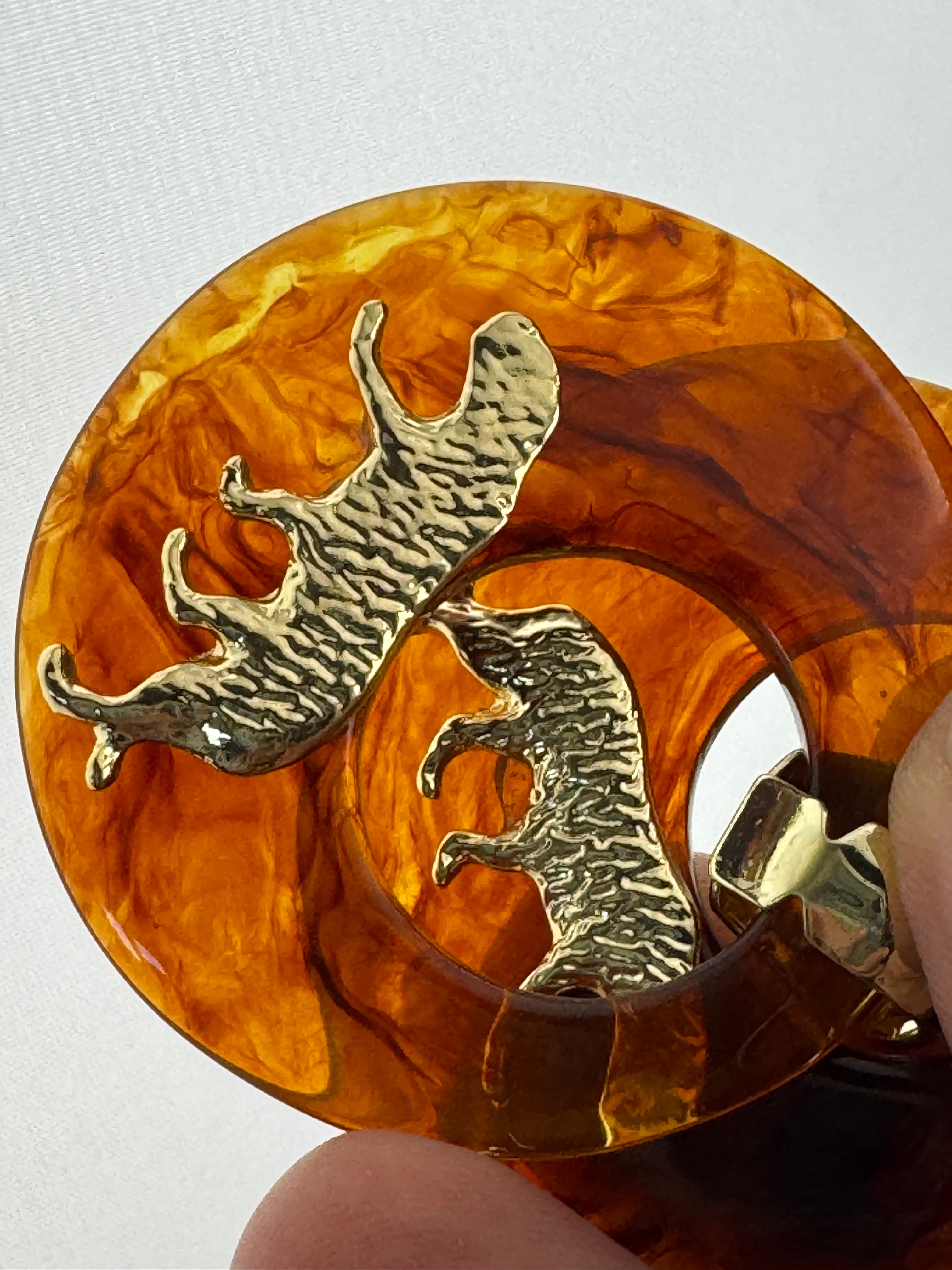Oversized brown tortoiseshell dangly acrylic hoop earrings with gold big cat leopards , pierced ears.