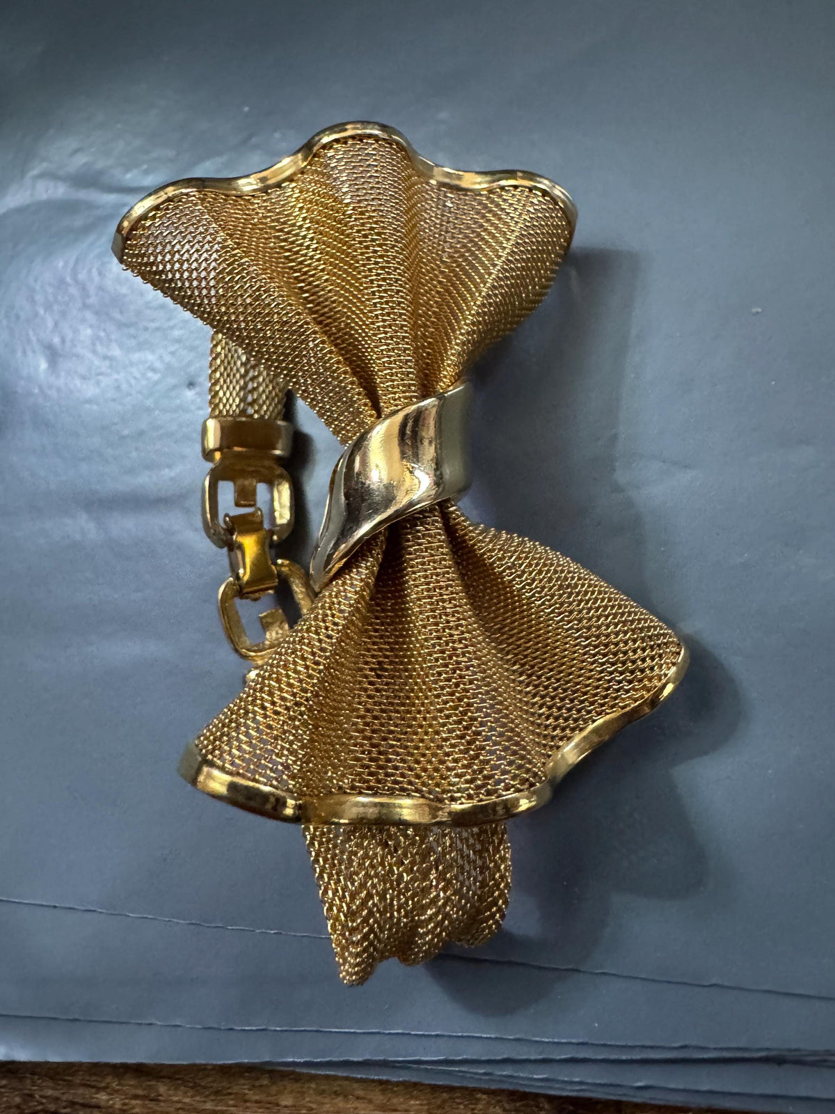 a gold-colored metal bracelet with a unique, ruffled design.
