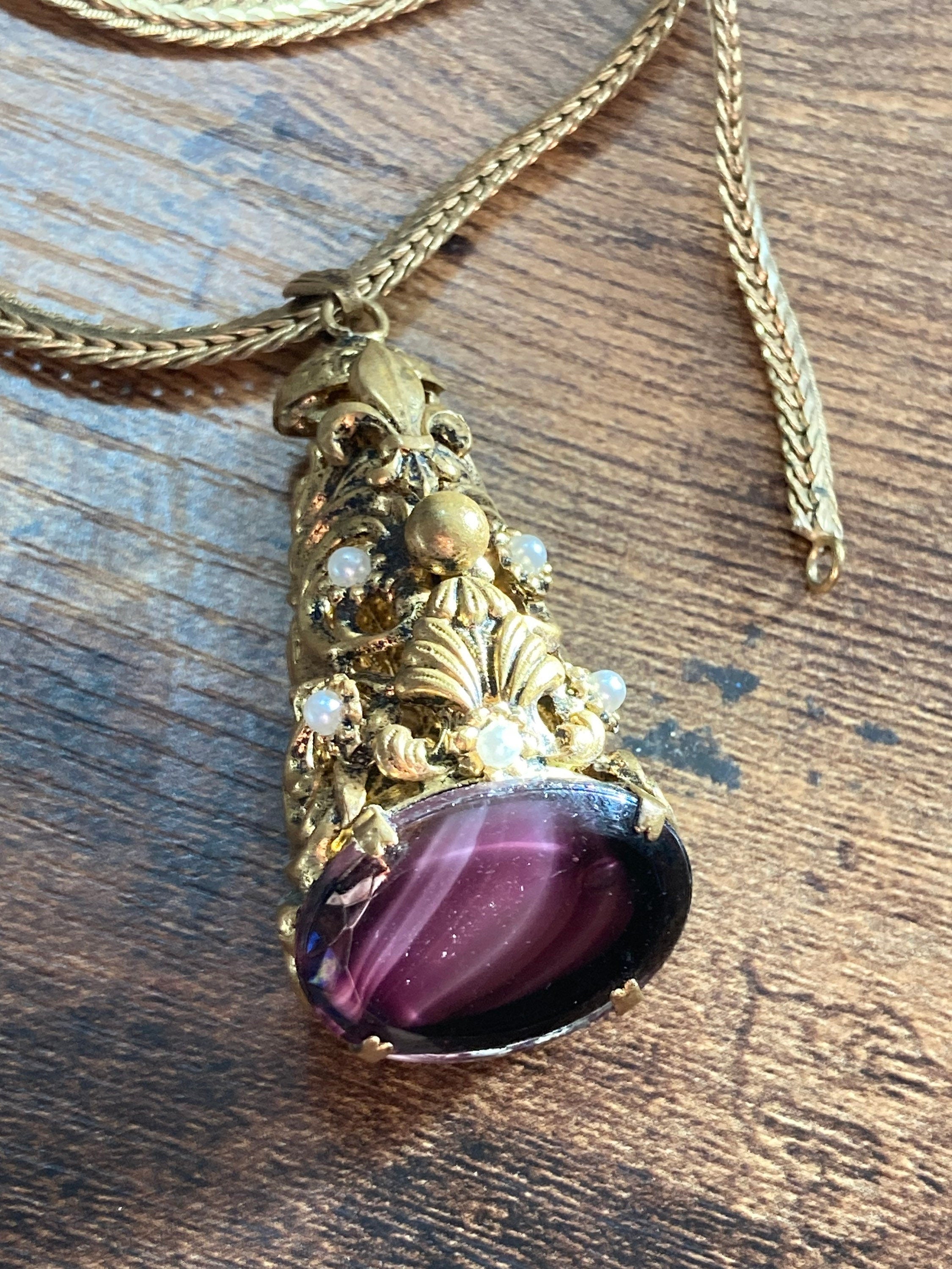 Vintage gold tone ornate gilt metal cone pendant with faux pearls and purple glass cabochon on flat chain