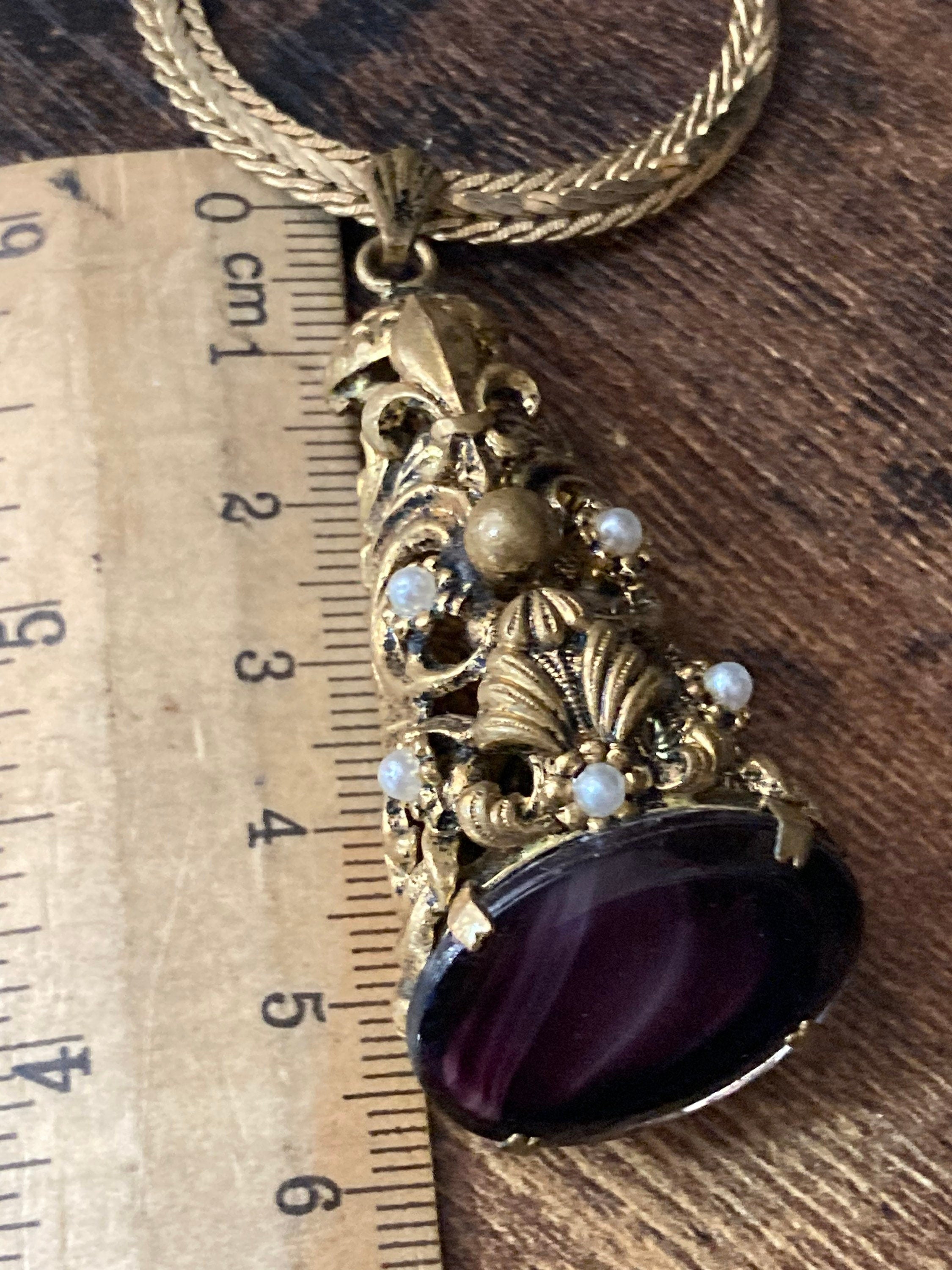 Vintage gold tone ornate gilt metal cone pendant with faux pearls and purple glass cabochon on flat chain