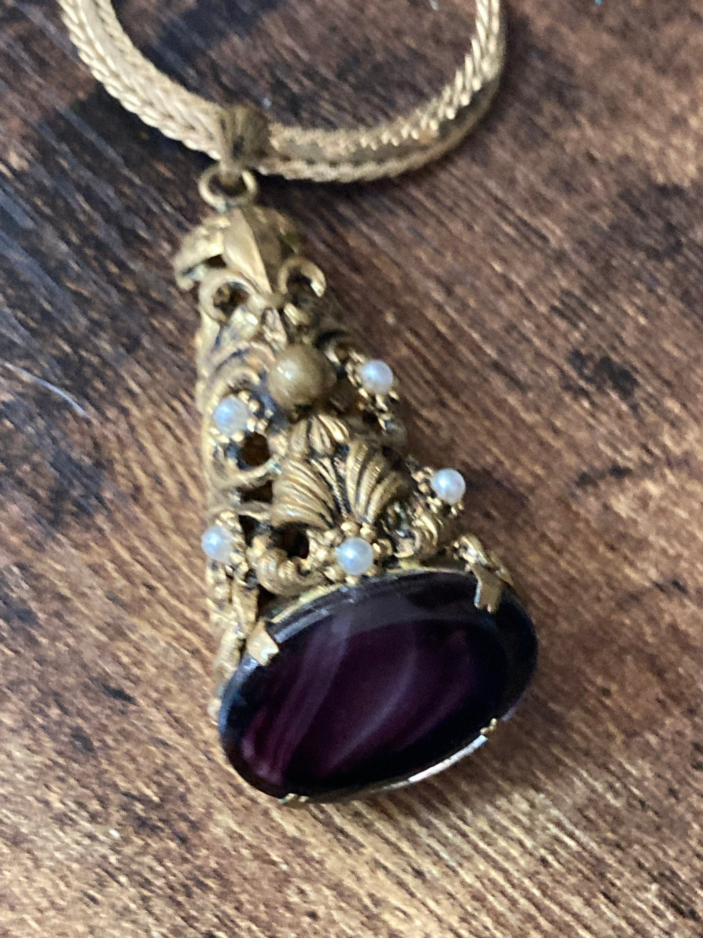 Vintage gold tone ornate gilt metal cone pendant with faux pearls and purple glass cabochon on flat chain