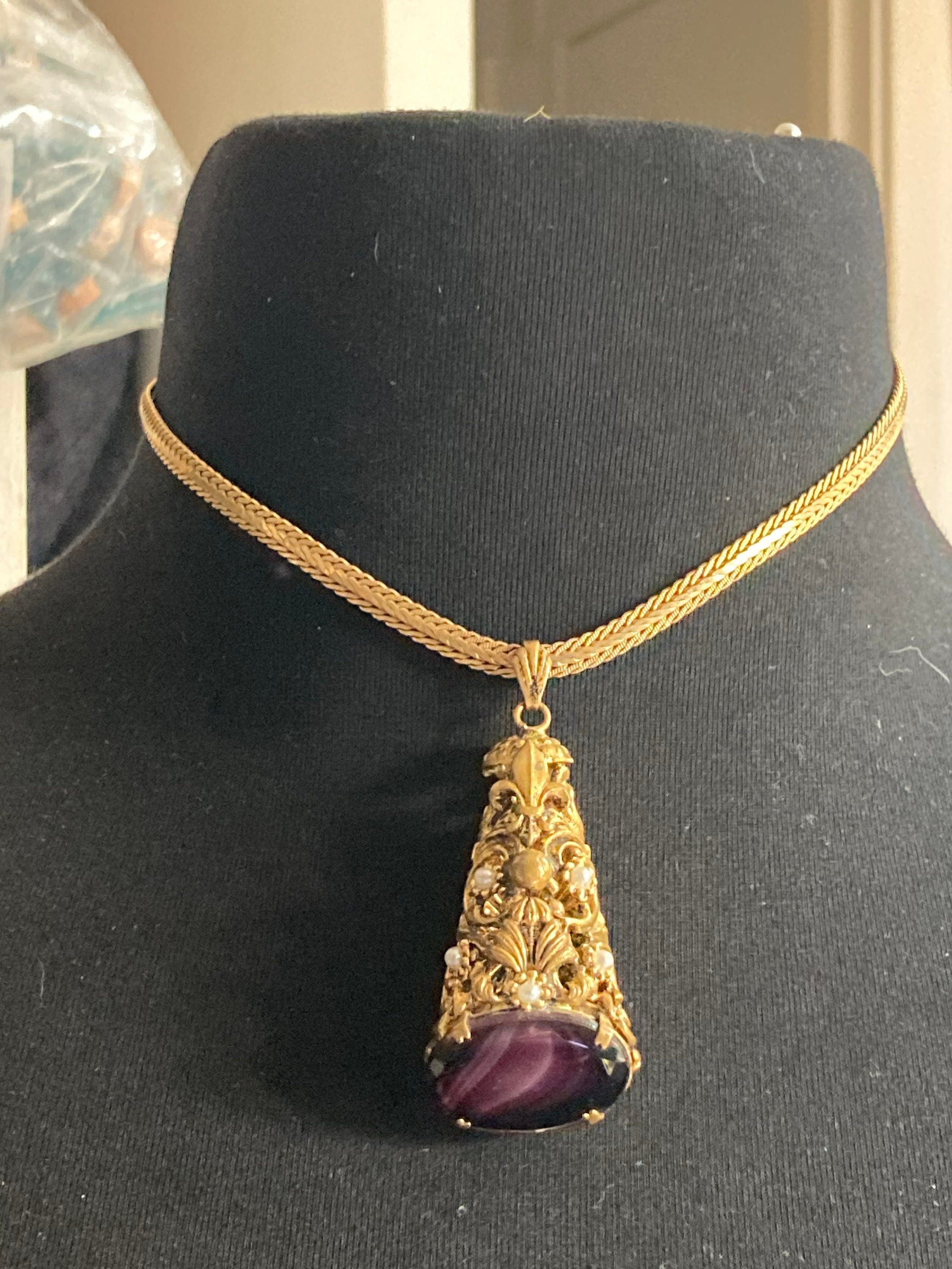 Vintage gold tone ornate gilt metal cone pendant with faux pearls and purple glass cabochon on flat chain