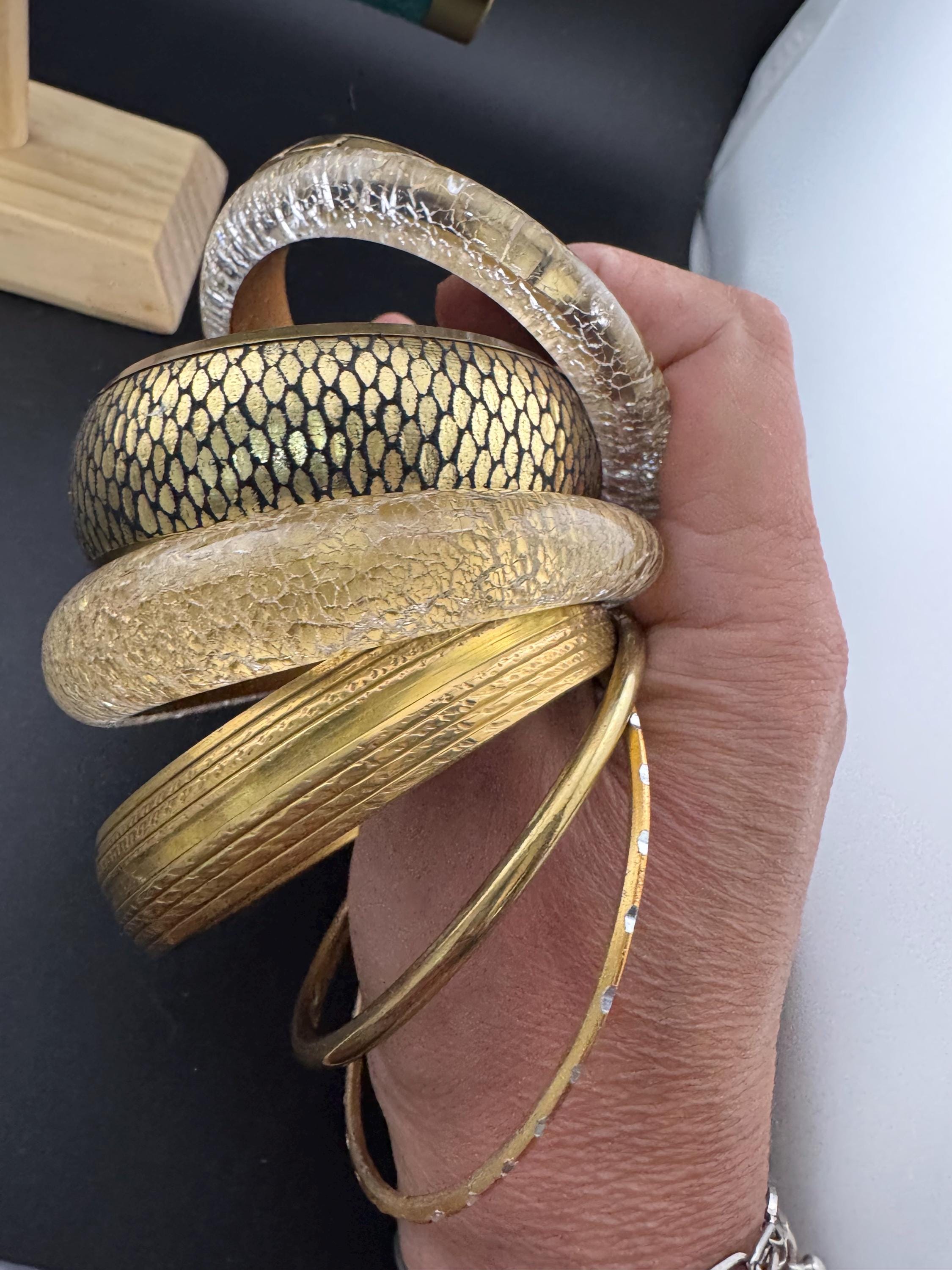 A curated set of vintage and retro mainly gold with black detail stacking bangles, boho festival bracelets