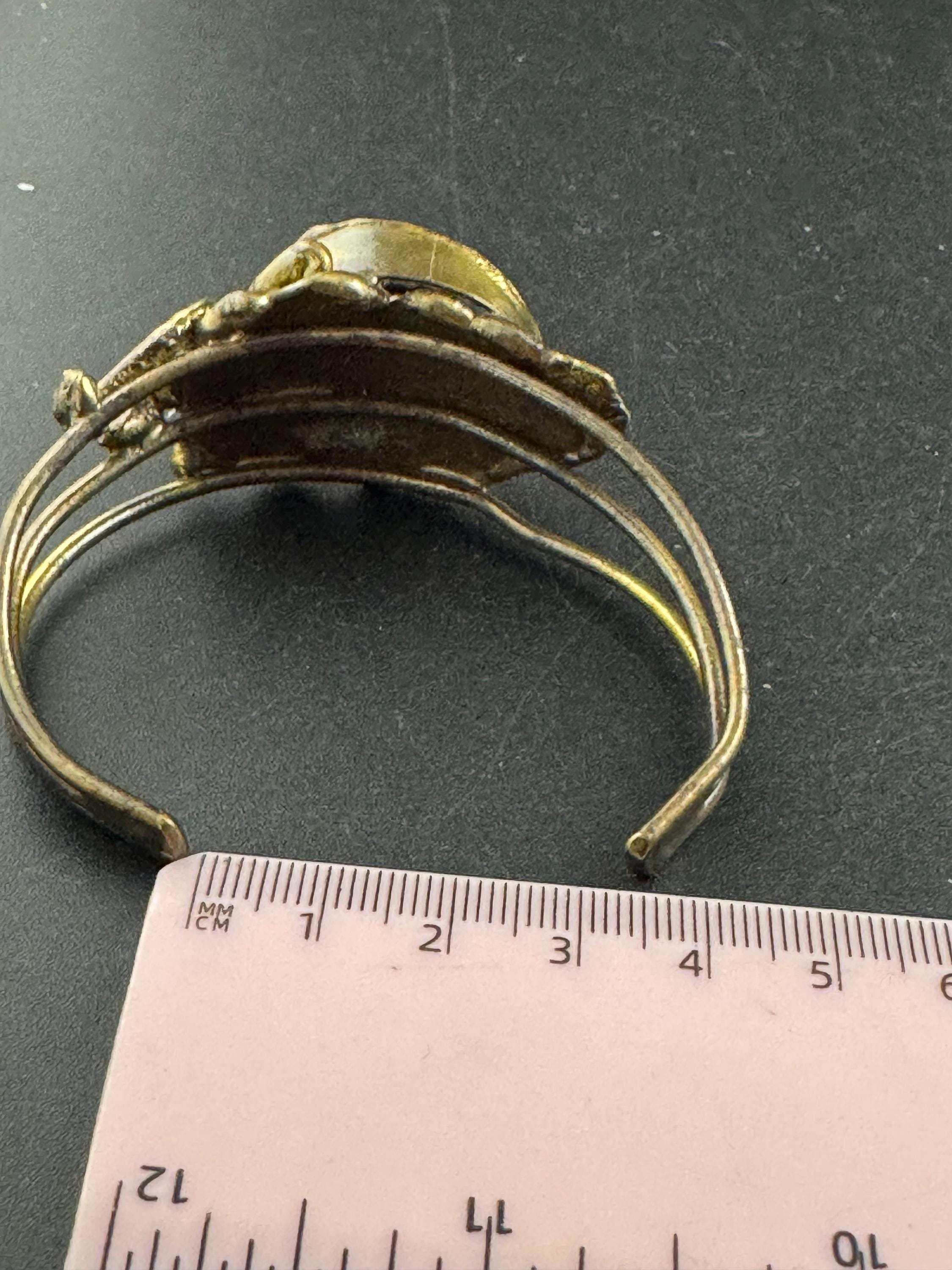 Artisan brass open bangle, set with green glass cabochon