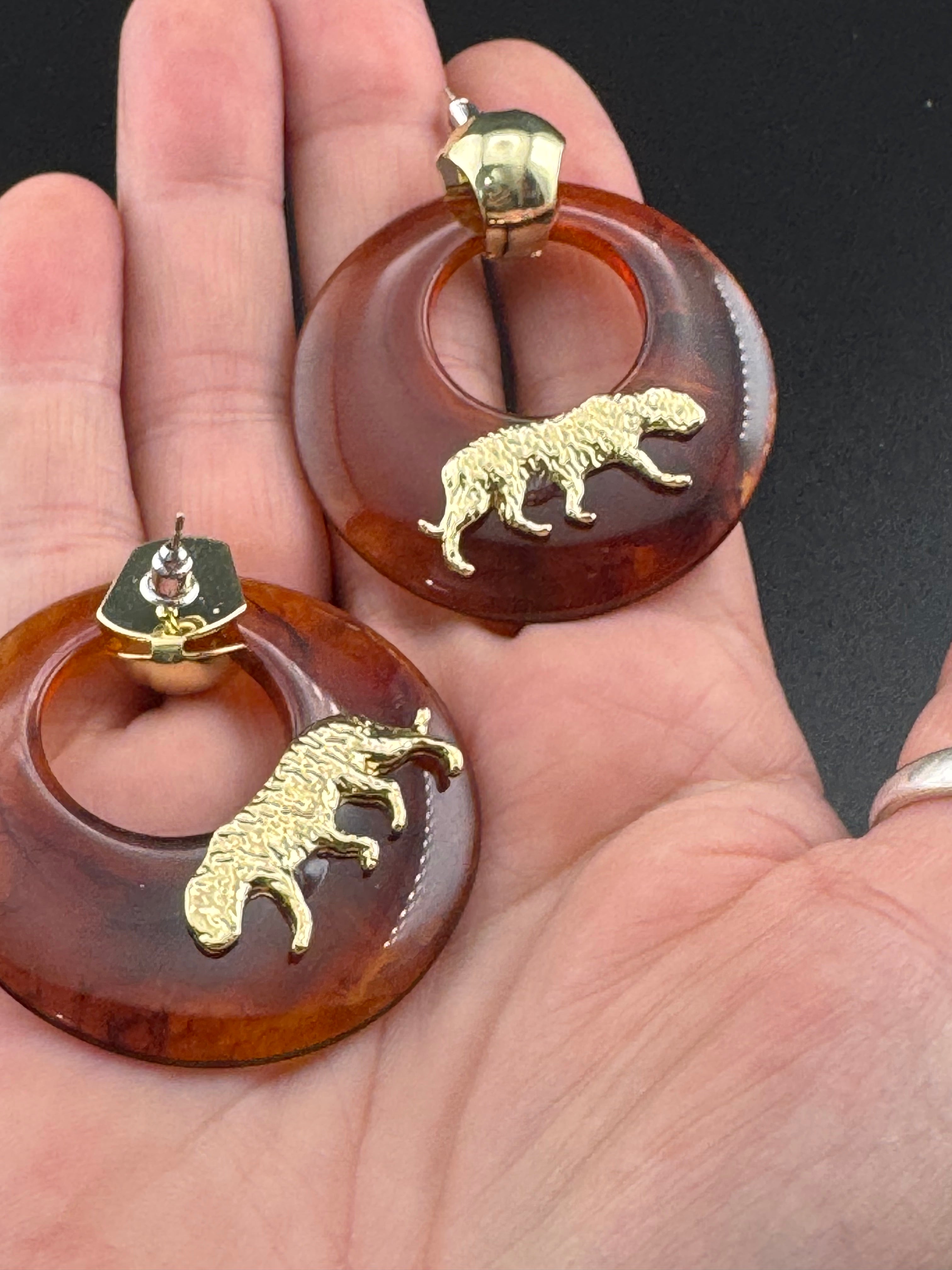 Oversized brown tortoiseshell dangly acrylic hoop earrings with gold big cat leopards , pierced ears.