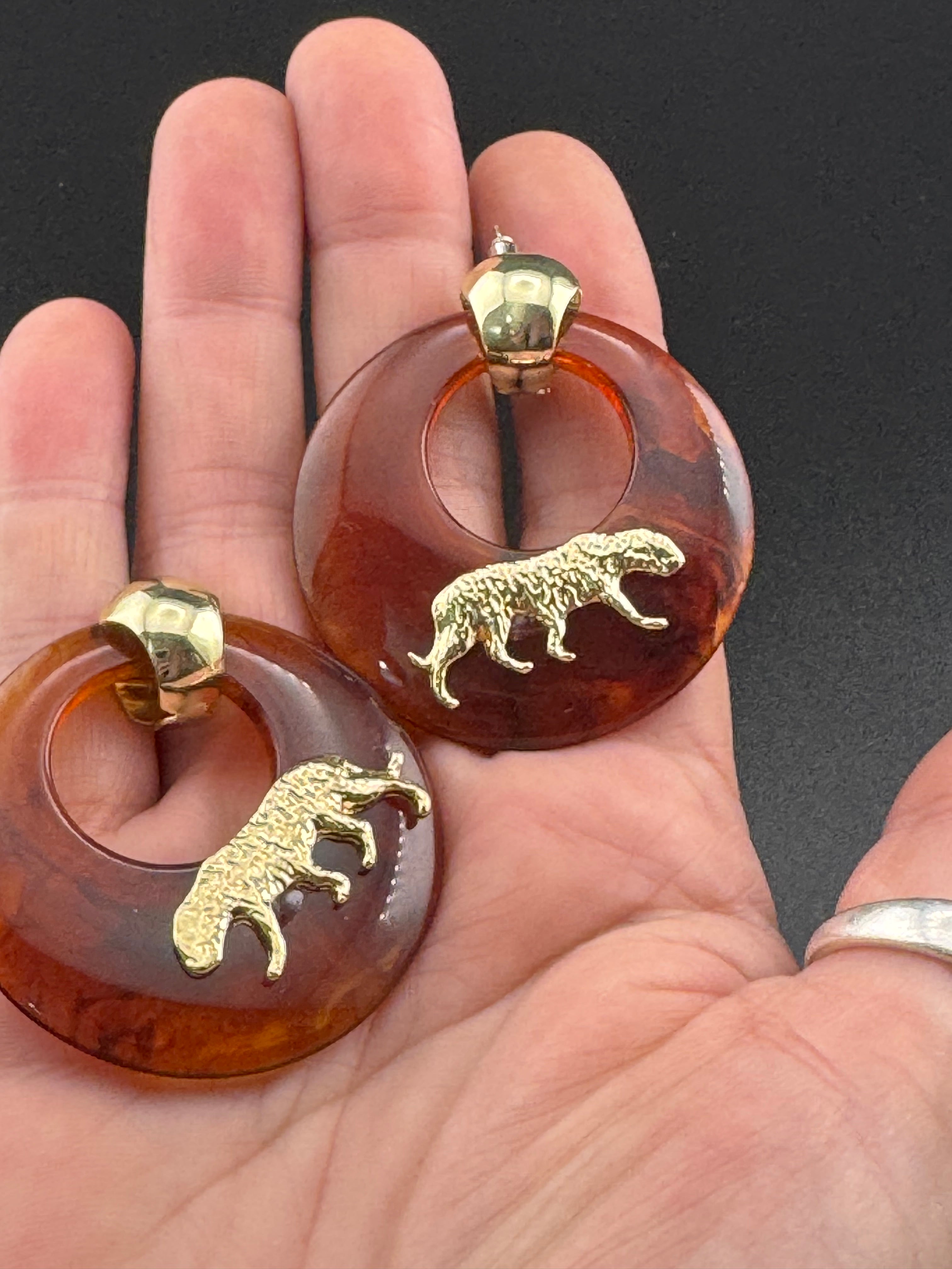 Oversized brown tortoiseshell dangly acrylic hoop earrings with gold big cat leopards , pierced ears.