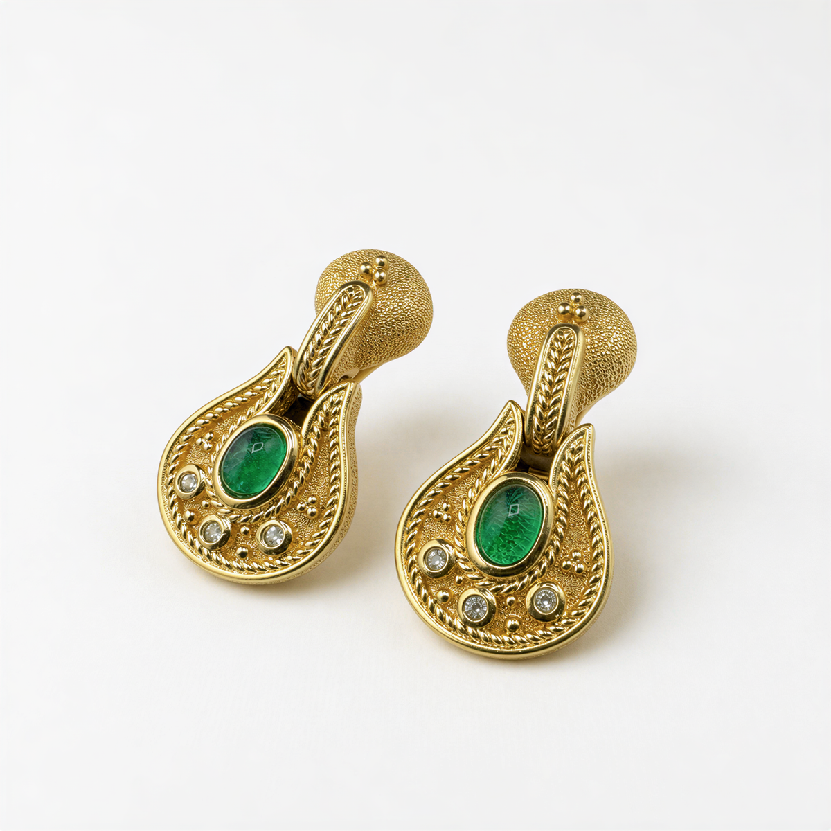 A pair of ornate gold earrings with green gemstones and small diamonds set in a decorative pattern.