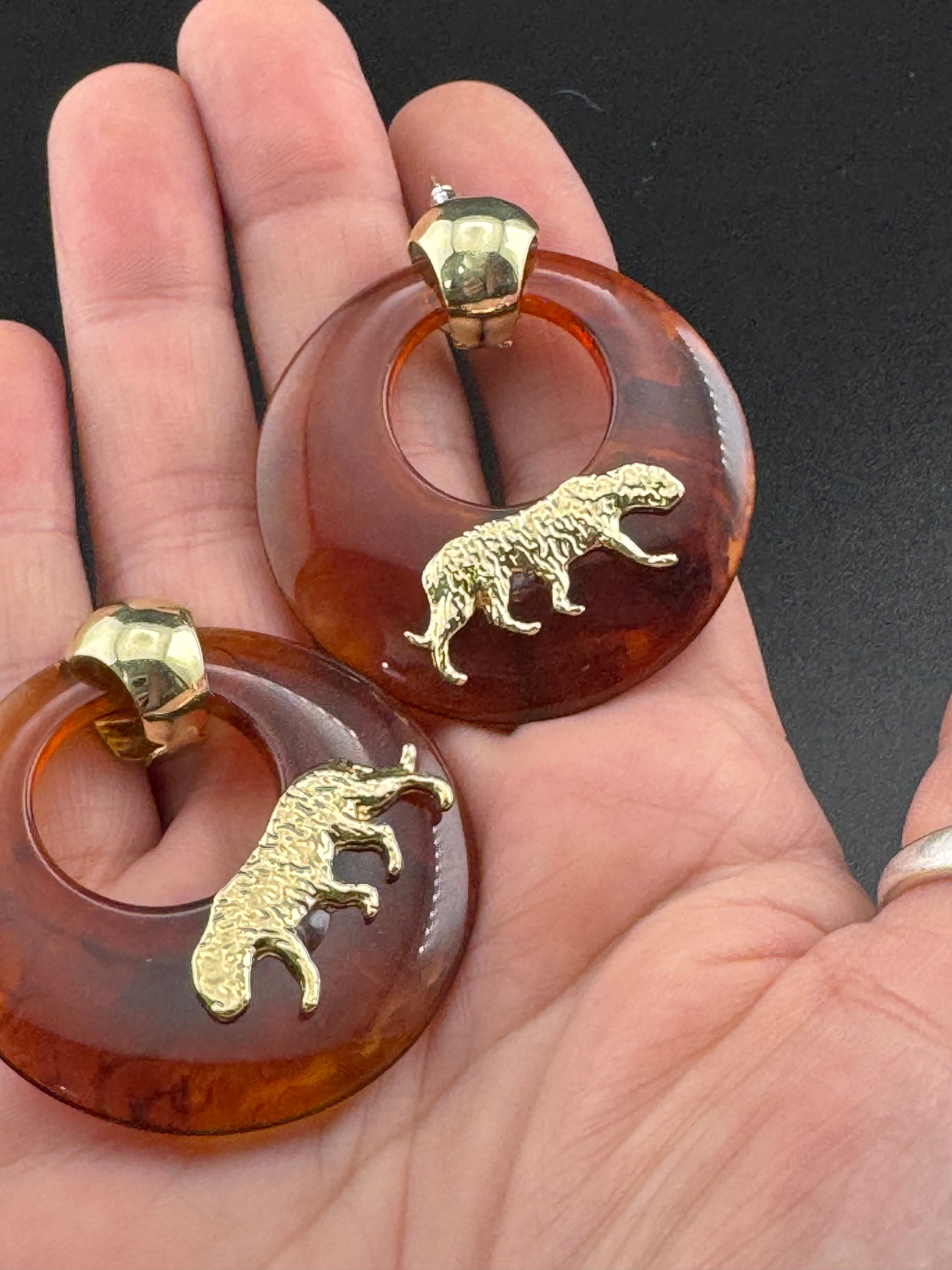 Oversized brown tortoiseshell dangly acrylic hoop earrings with gold big cat leopards , pierced ears.