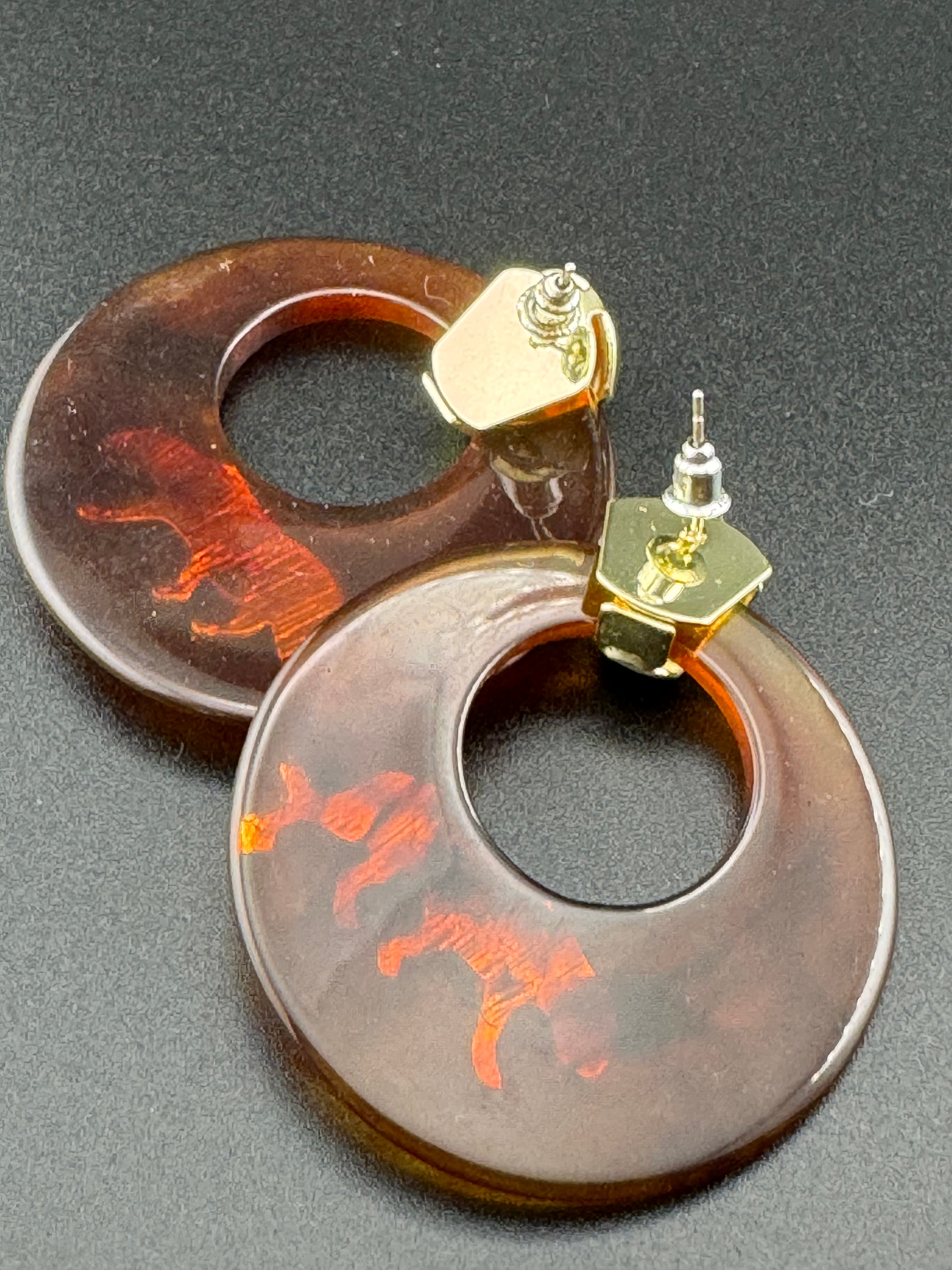 Oversized brown tortoiseshell dangly acrylic hoop earrings with gold big cat leopards , pierced ears.
