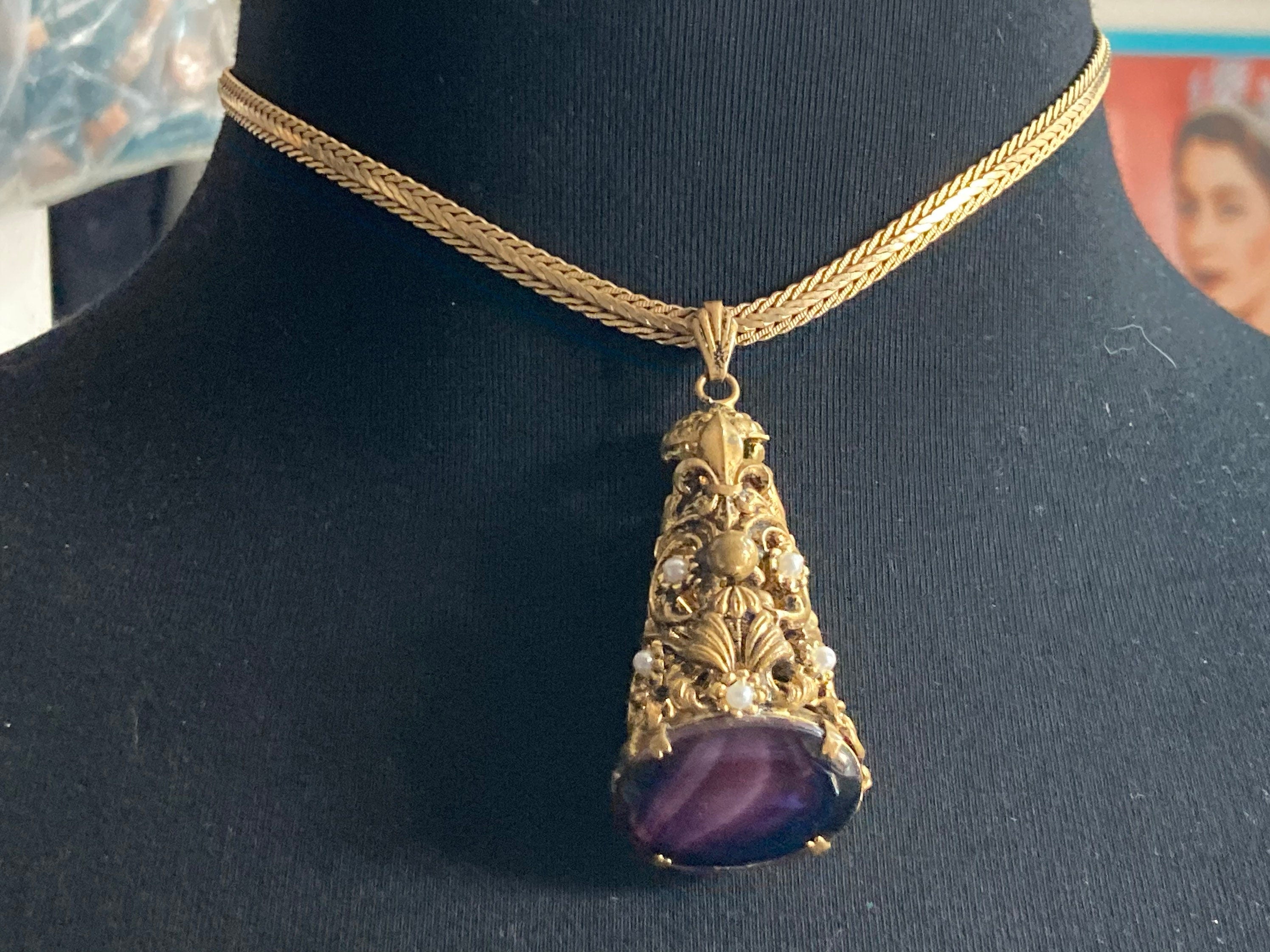 Vintage gold tone ornate gilt metal cone pendant with faux pearls and purple glass cabochon on flat chain