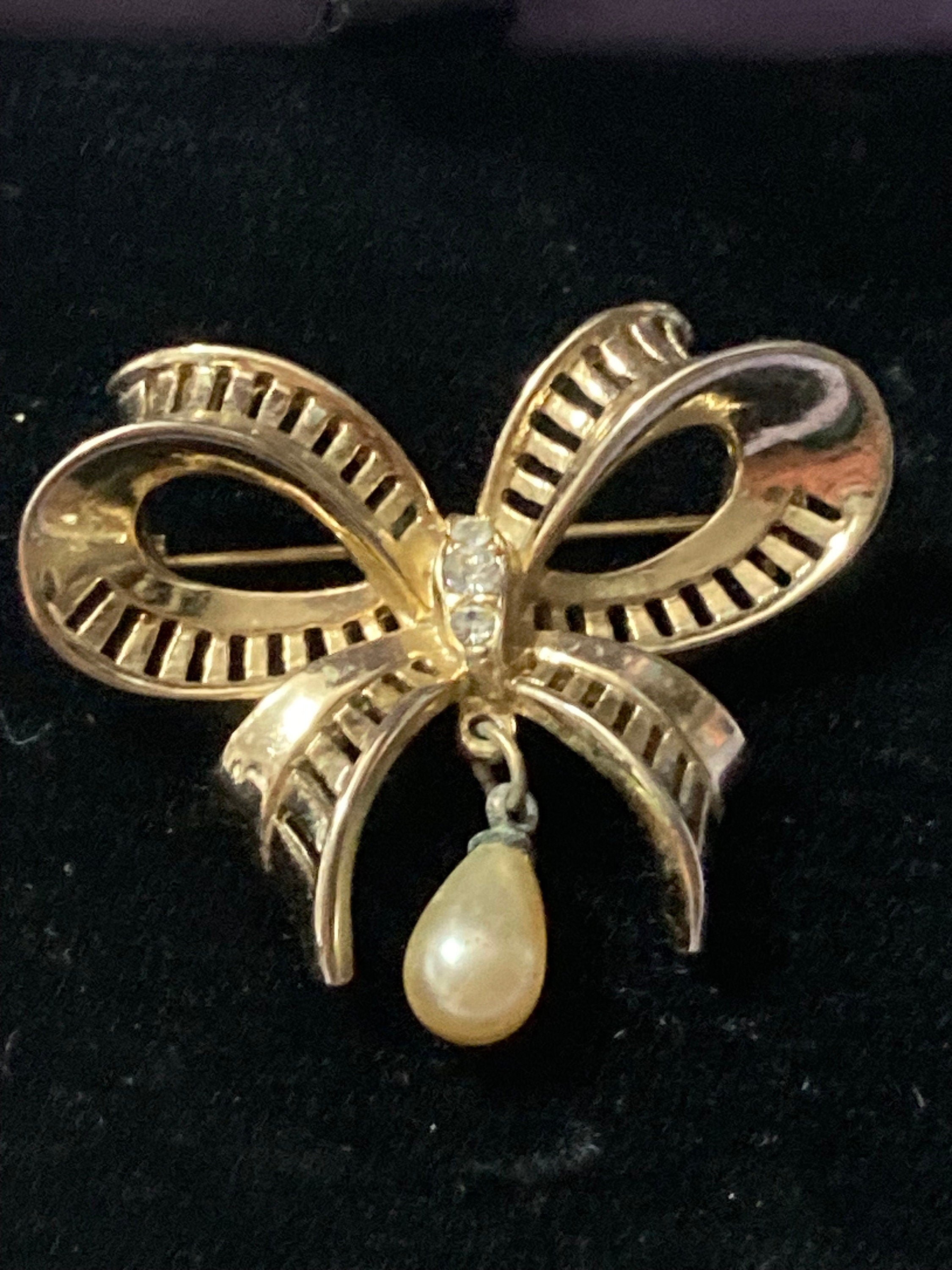 Vintage open work gold tone ribbon bow brooch with faux pearl dropper modernist