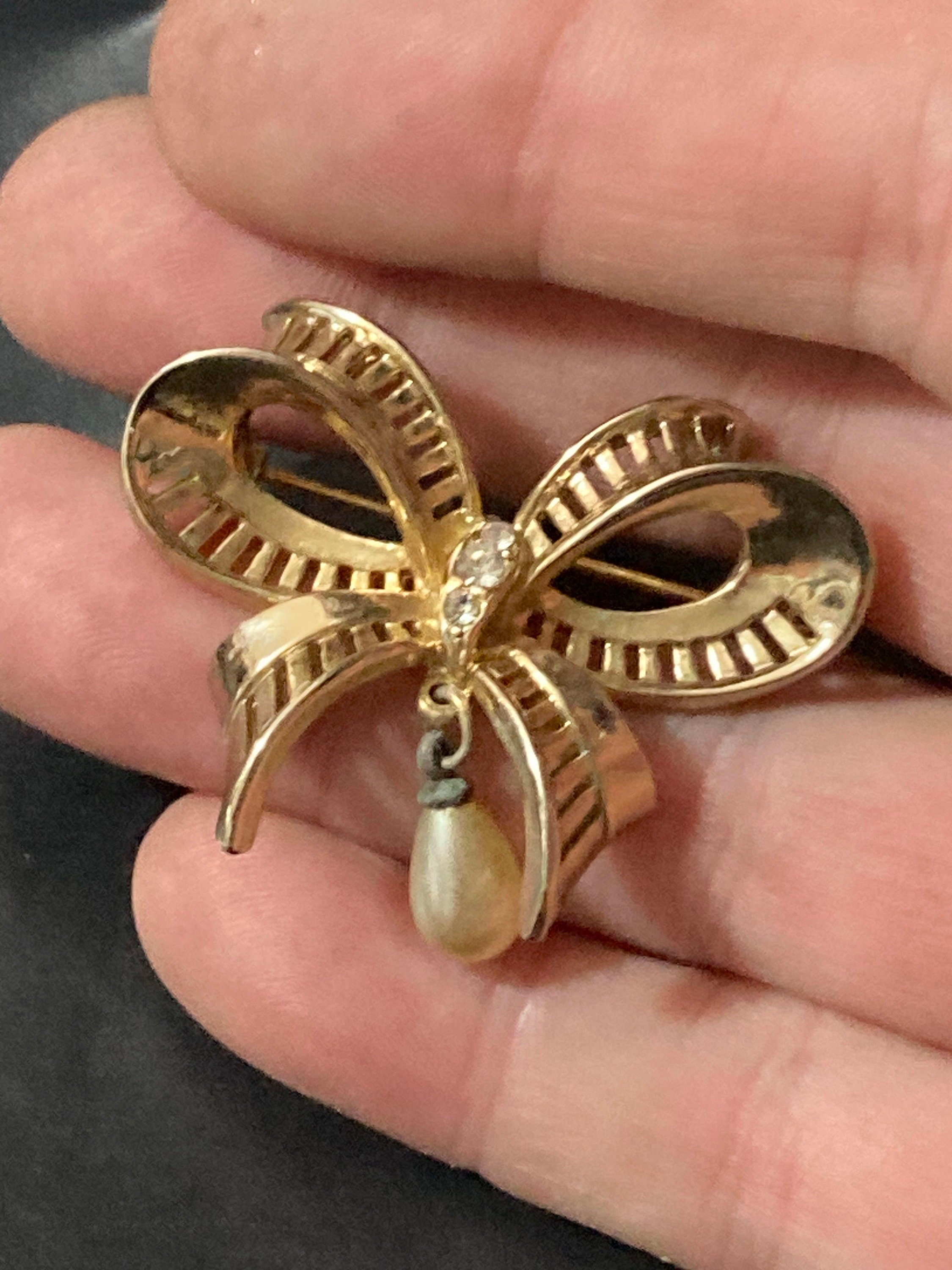 Vintage open work gold tone ribbon bow brooch with faux pearl dropper modernist