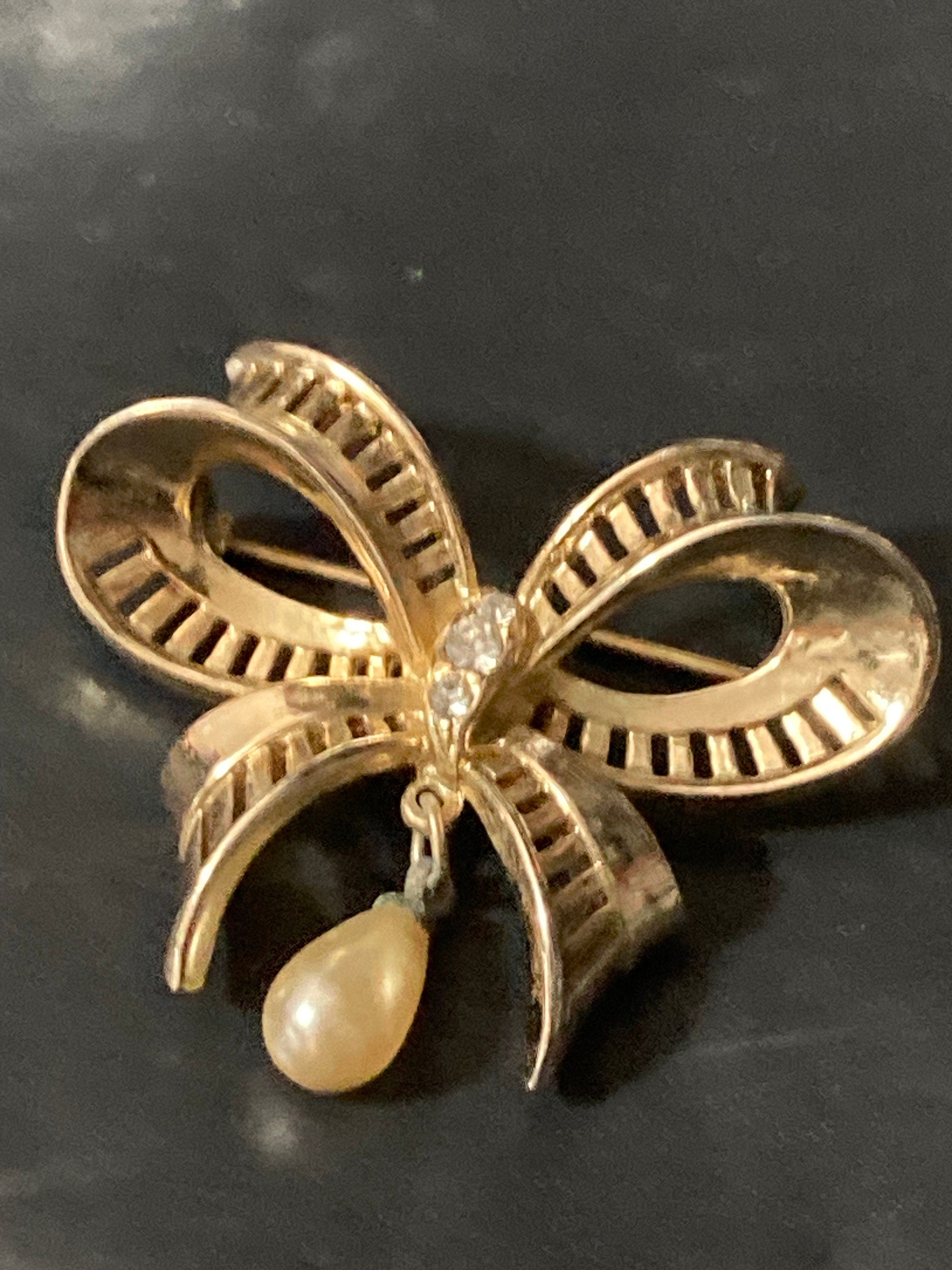 Vintage open work gold tone ribbon bow brooch with faux pearl dropper modernist