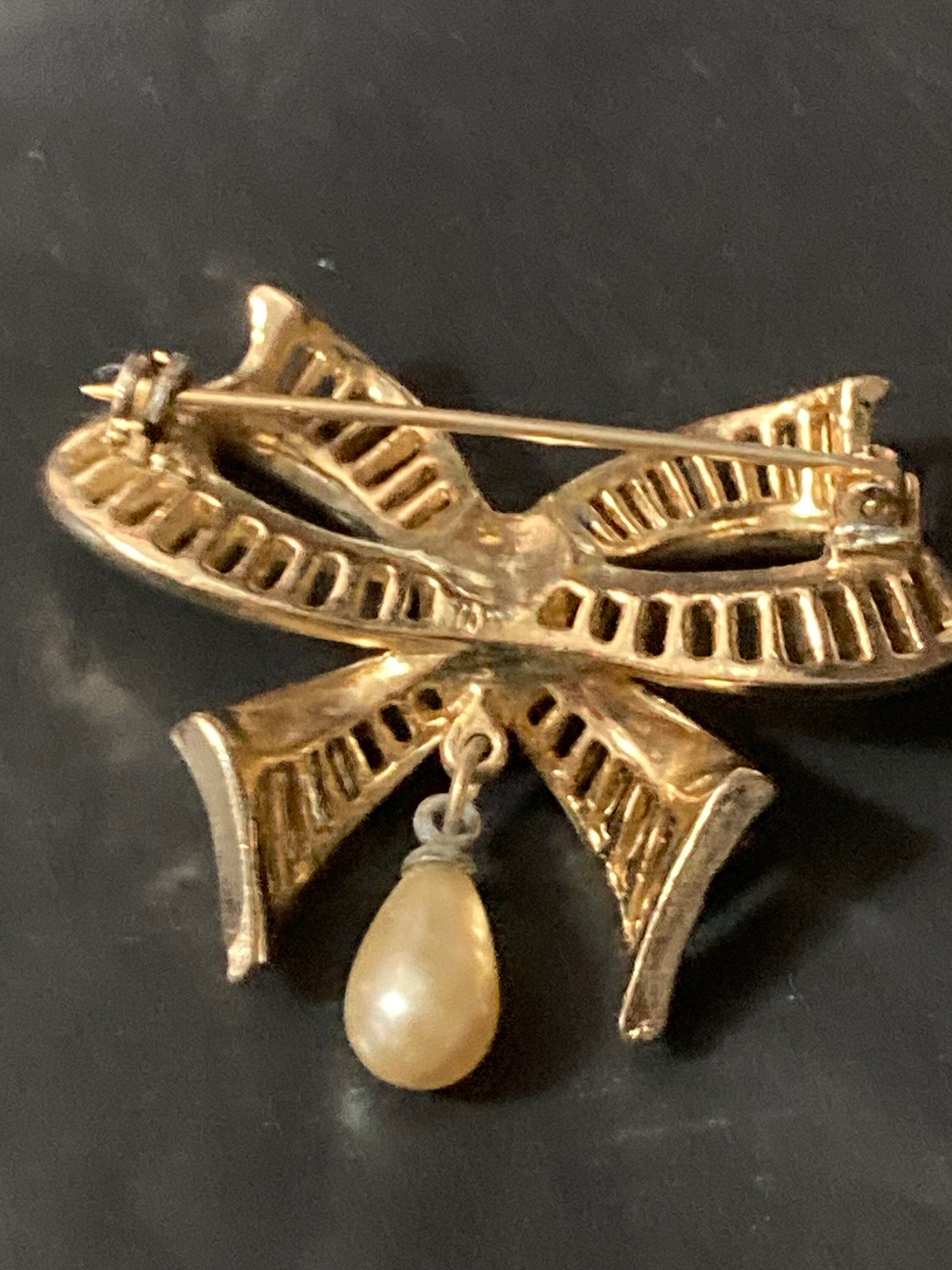 Vintage open work gold tone ribbon bow brooch with faux pearl dropper modernist