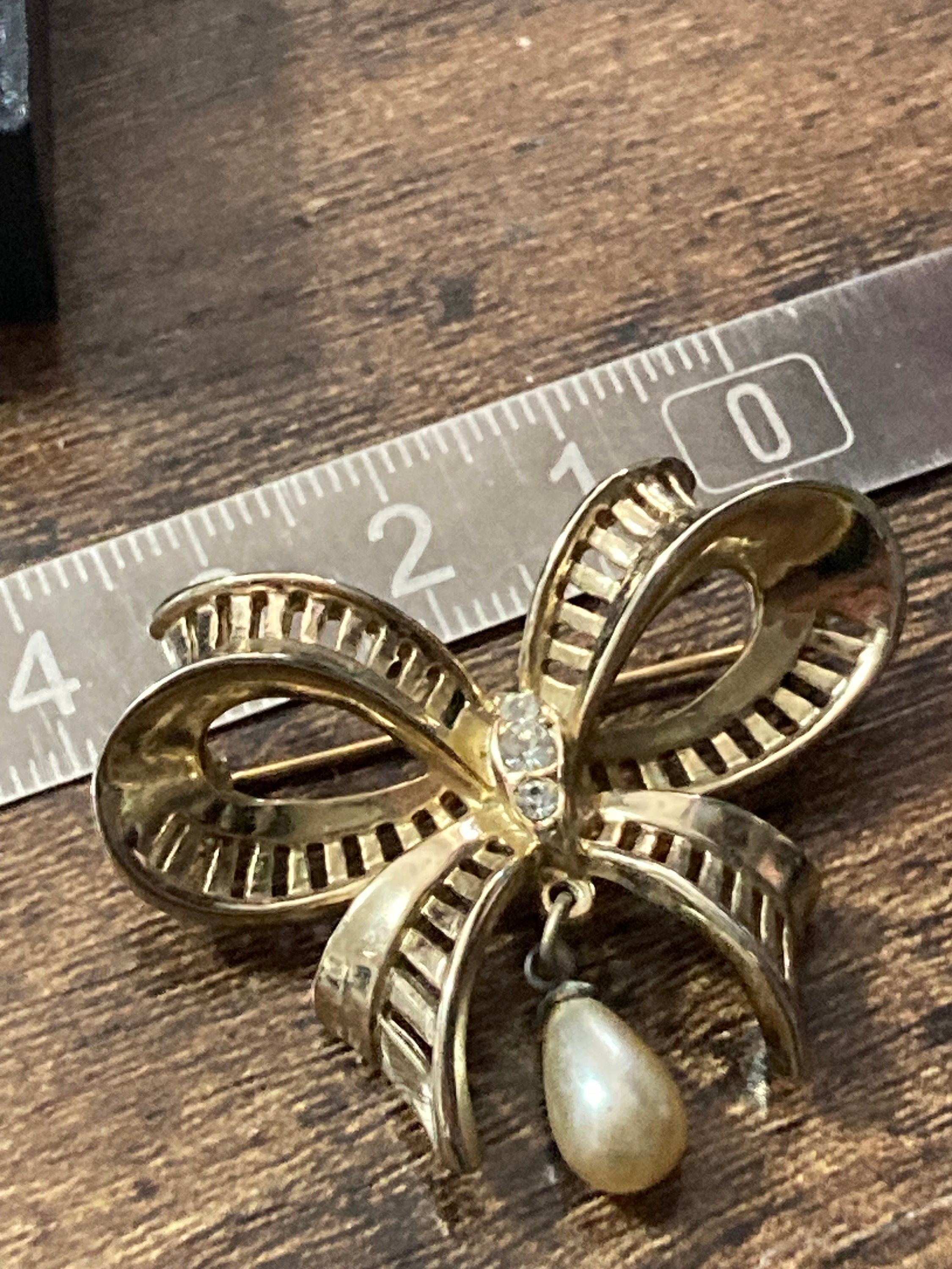 Vintage open work gold tone ribbon bow brooch with faux pearl dropper modernist