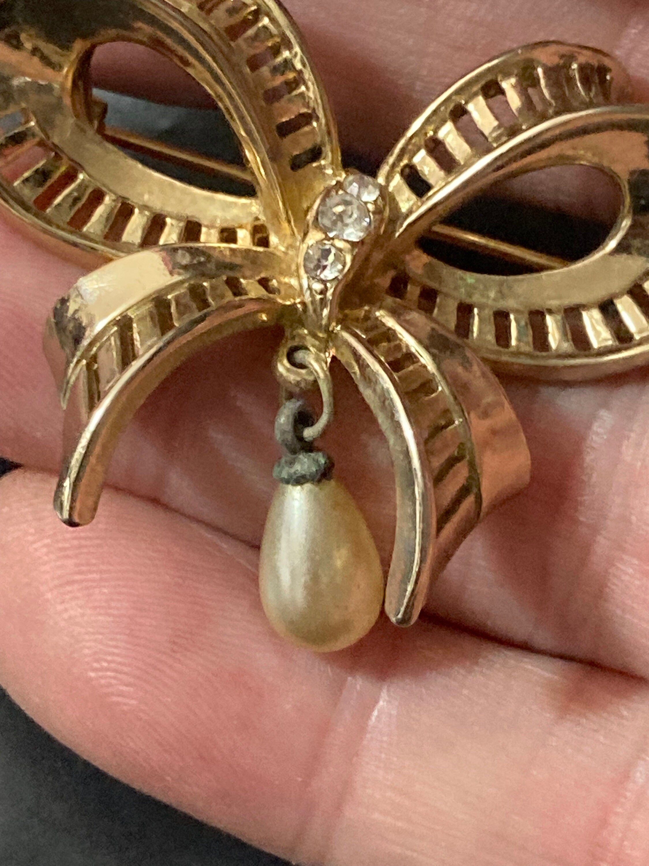 Vintage open work gold tone ribbon bow brooch with faux pearl dropper modernist