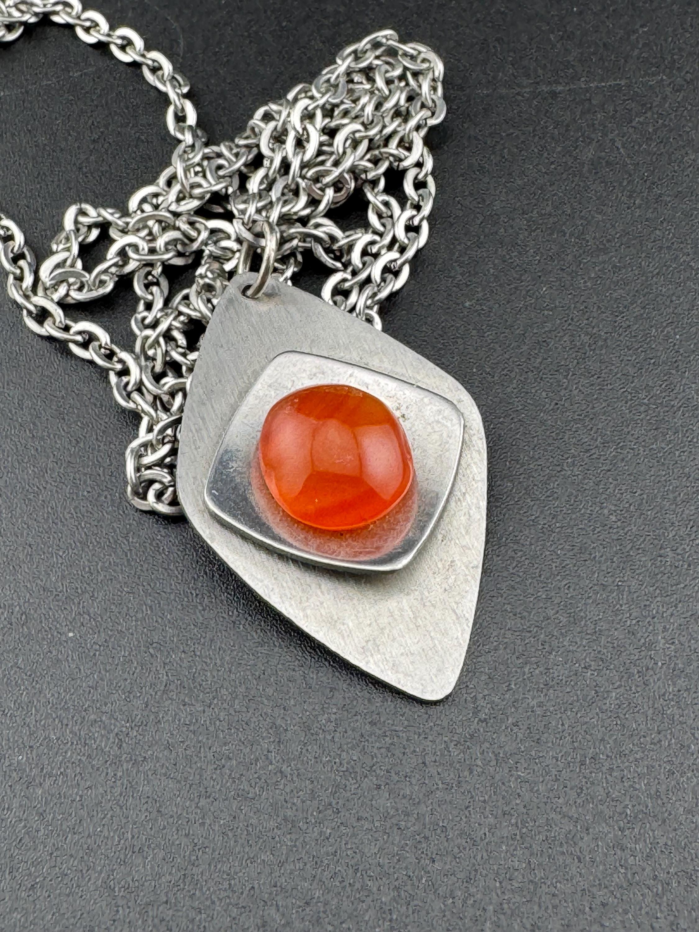 Vintage Modernist silver tone stainless steel pendant necklace and chain set with central orange glass cabochon 1970s