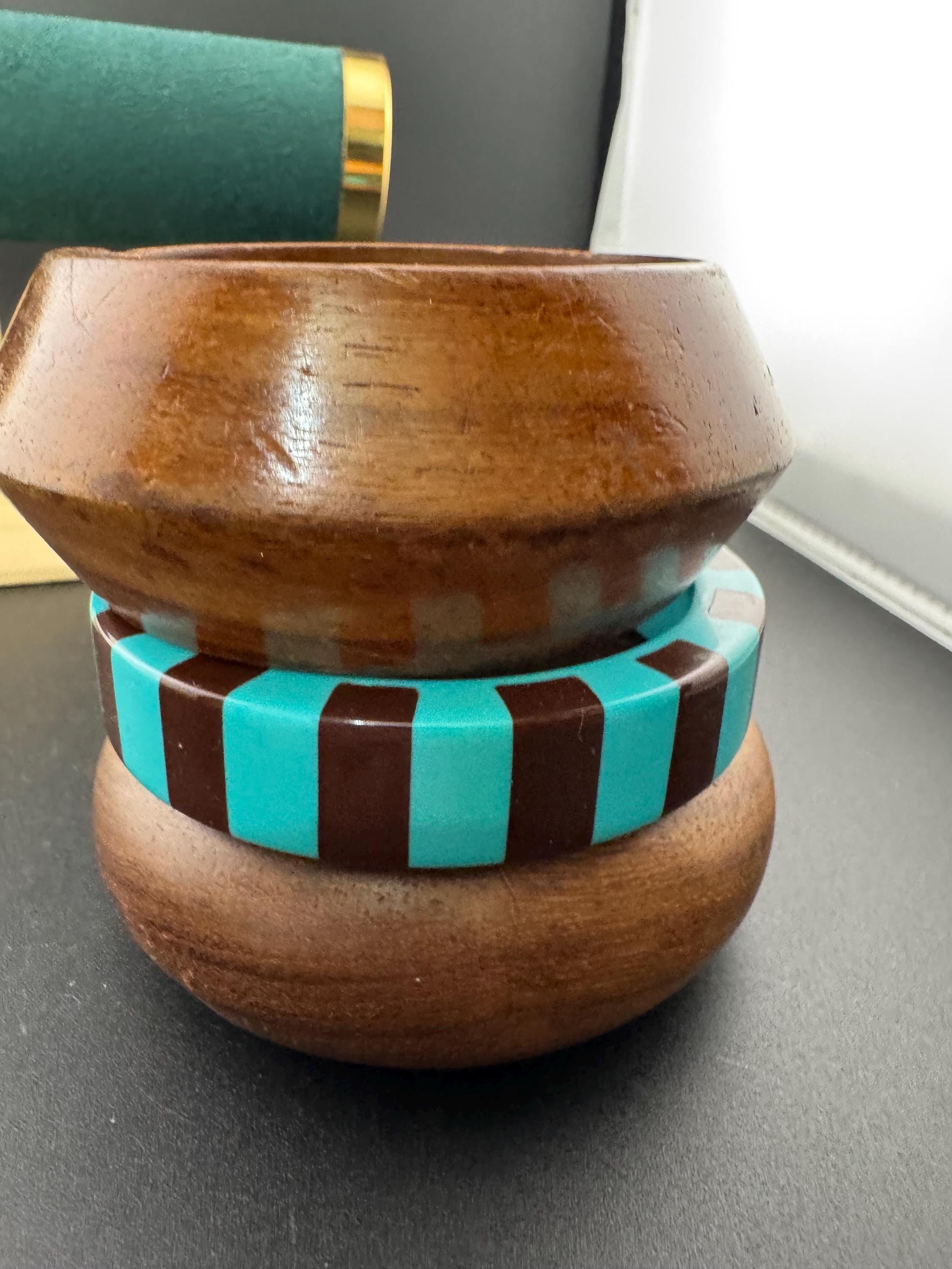 A curated stack of turquoise blue and brown vintage retro plastic and wooden bangles