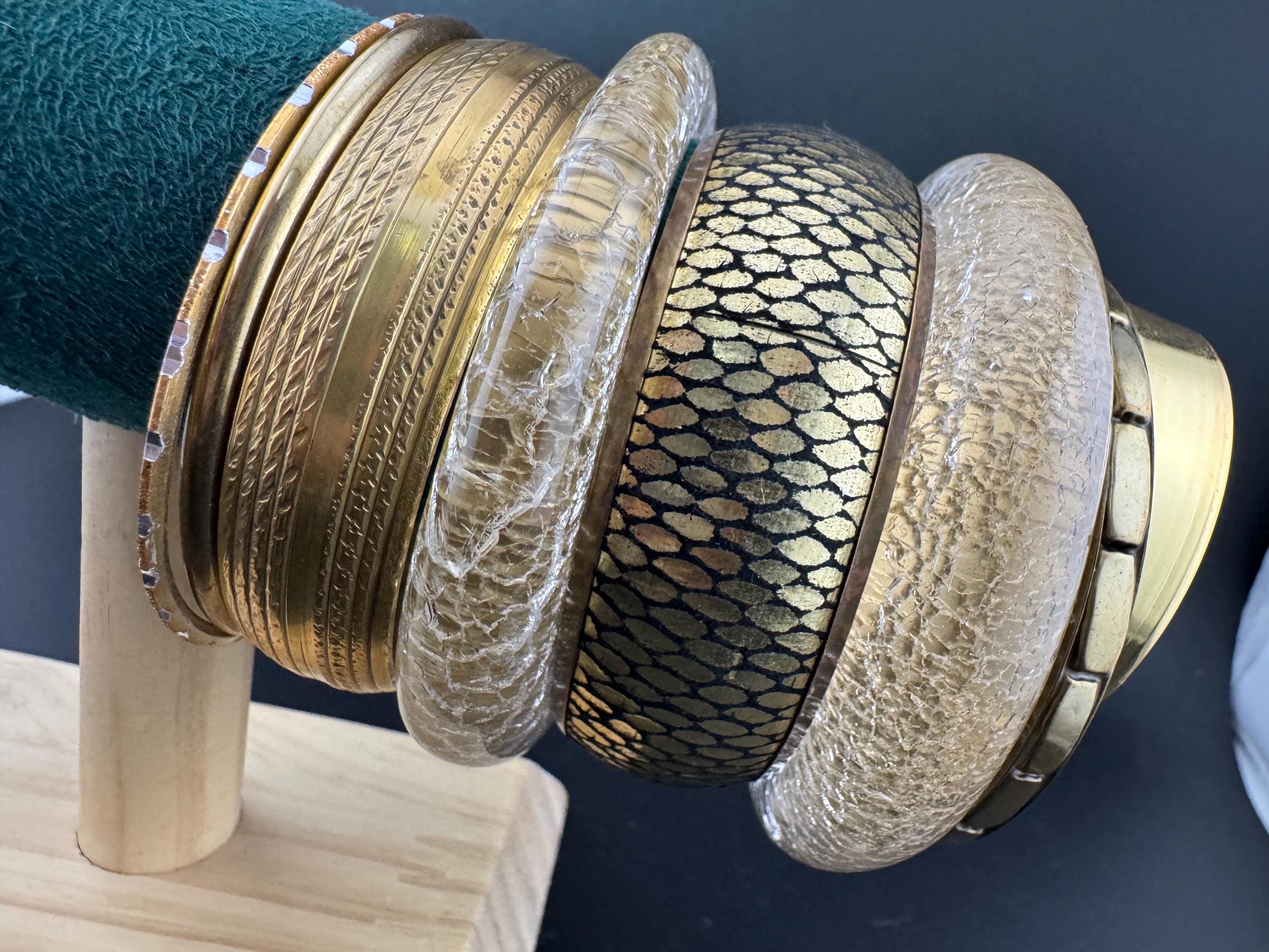 A curated set of vintage and retro mainly gold with black detail stacking bangles, boho festival bracelets