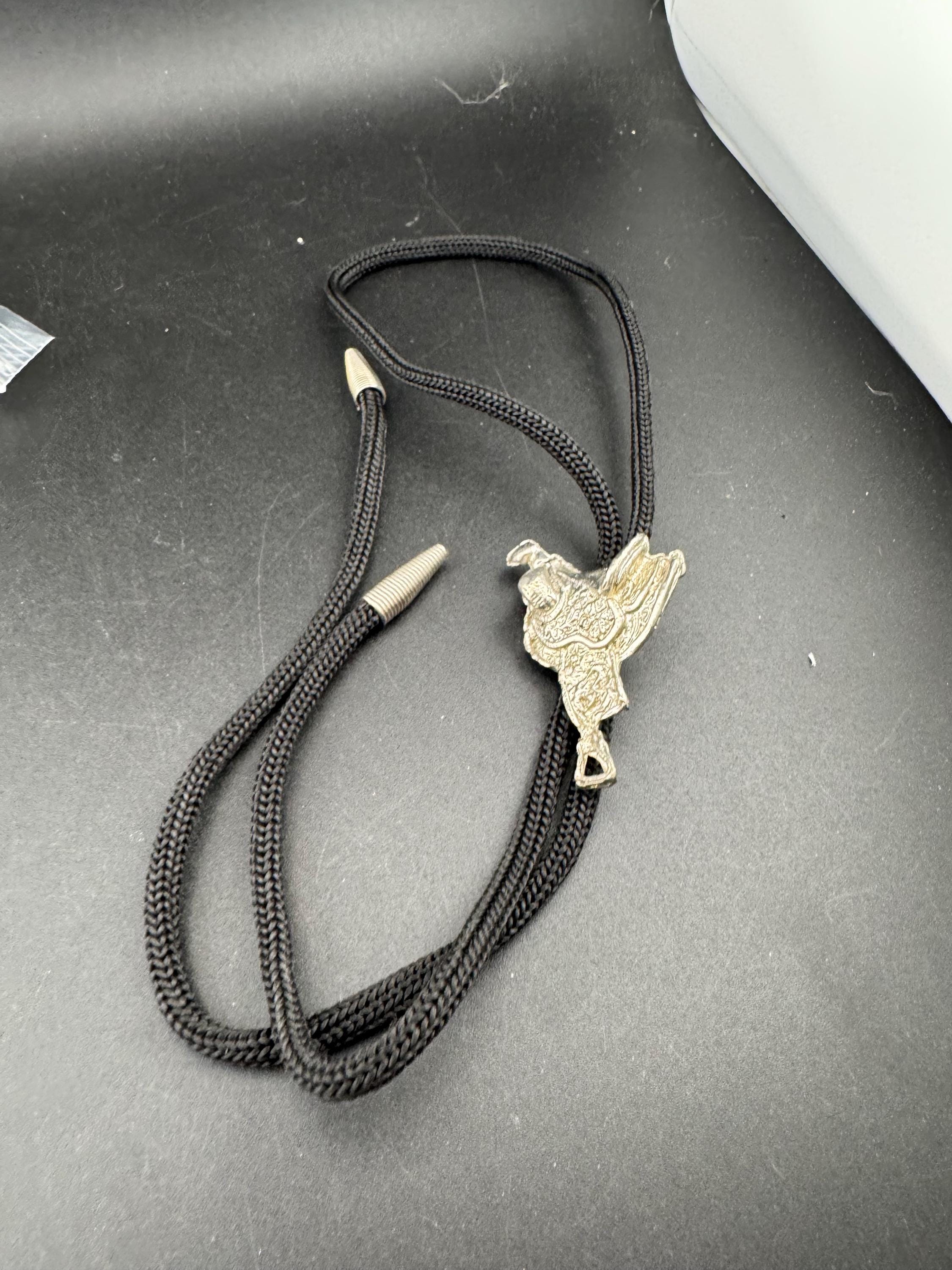 Retro western style horse saddle bolo tie with black woven leather