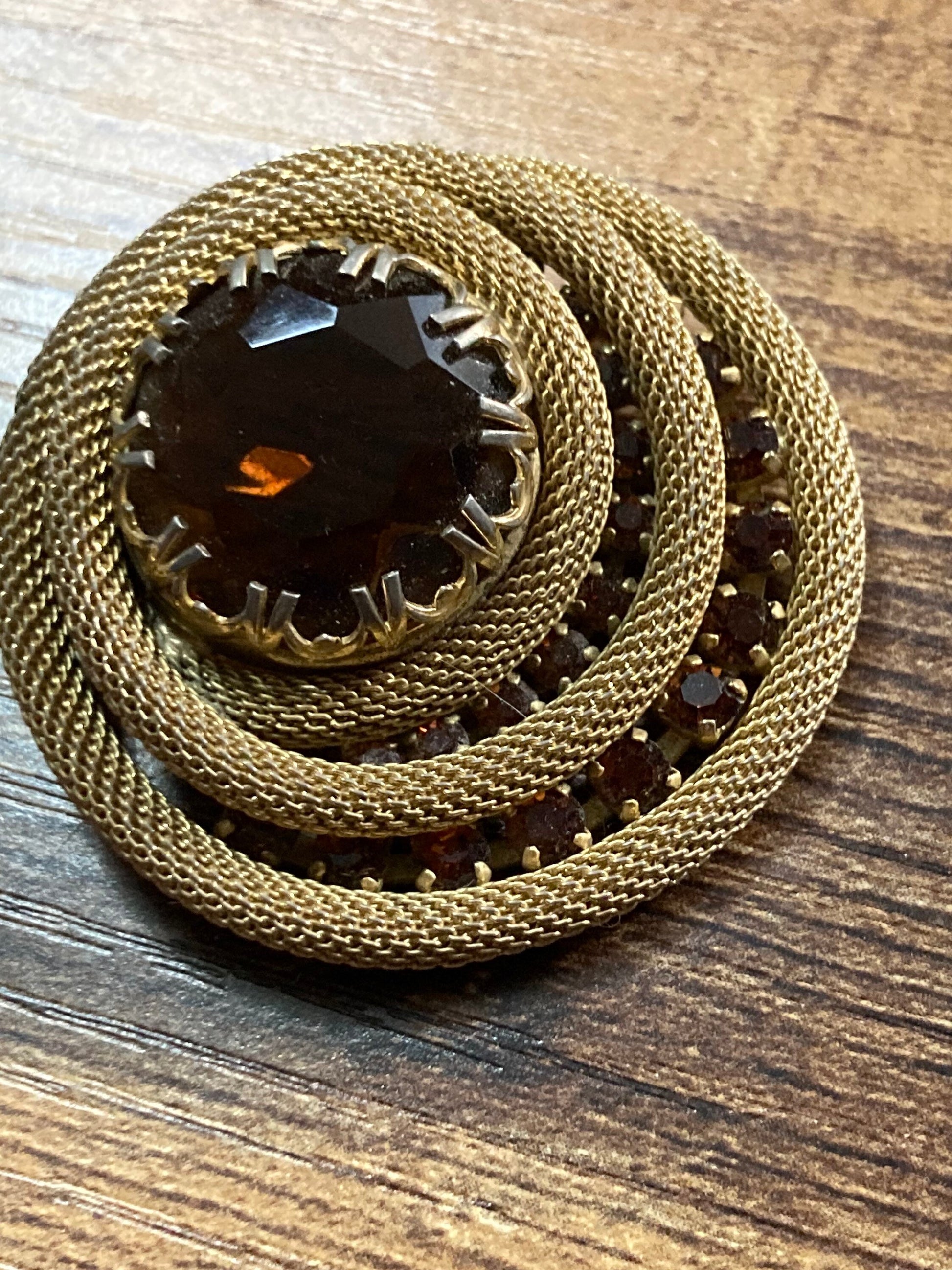 Vintage 4.5cm gold tone mesh brooch with brown amber glass faceted central cabochon.